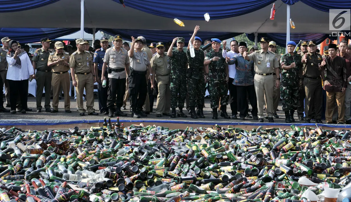 Gubernur DKI Jakarta, Anies Baswedan bersama pejabat kepolisian, TNI, Satpol PP dan Kejaksaan melemparkan botol minuman keras (miras) ilegal sebelum dimusnahkan di Lapangan Silang Monas Tenggara, Senin (27/5/2019). Pemprov DKI memusnahkan 18.174 botol miras tanpa izin. (merdeka.com/Iqbal S Nugroho)