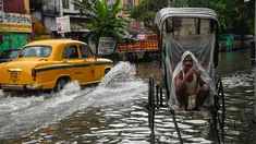 Seorang penarik becak membungkus dirinya dengan lembaran plastik sambil menunggu untuk mengangkut pelanggan melintasi jalan yang tergenang air setelah hujan lebat di Kolkata (20/9/2021). Hujan dilaporkan dipicu oleh sirkulasi siklon yang terbentuk di atas Teluk Benggala. (AFP/Dibyangshu Sarkar)