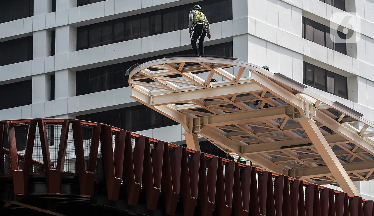 Aktivitas pengerjaan revitalisasi Jembatan Penyeberangan Orang (JPO) di Jalan Sudirman, Jakarta, Minggu (19/12/2021). JPO yang dibangun ulang dengan konsep kapal pinisi dilengkapi jalur sepeda ini didedikasikan untuk mengenang perjuangan tenaga kesehatan selama pandemi. (Liputan6.com/JohanTallo)