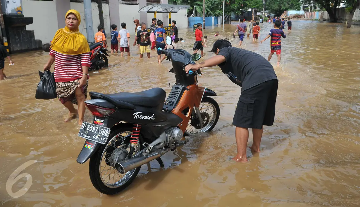 Warga memanfaatkan air banjir yang merendam kawasan Tebet, Jakarta, untuk mencuci motor, Selasa (8/3/2016). Banjir akibat luapan Kali Ciliwung tersebut merendam kawasan itu sejak pagi tadi. (Liputan6.com/Gempur M Surya)