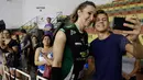 Seorang fans berselfie dengan Tiffany Abreu usai pertandingan liga voli Brasil di Bauru, Brasil,(19/12). Abreu, seorang transgender, mendapat otorisasi untuk bermain di liga voli wanita teratas negara tersebut. (AP Photo / Andre Penner)