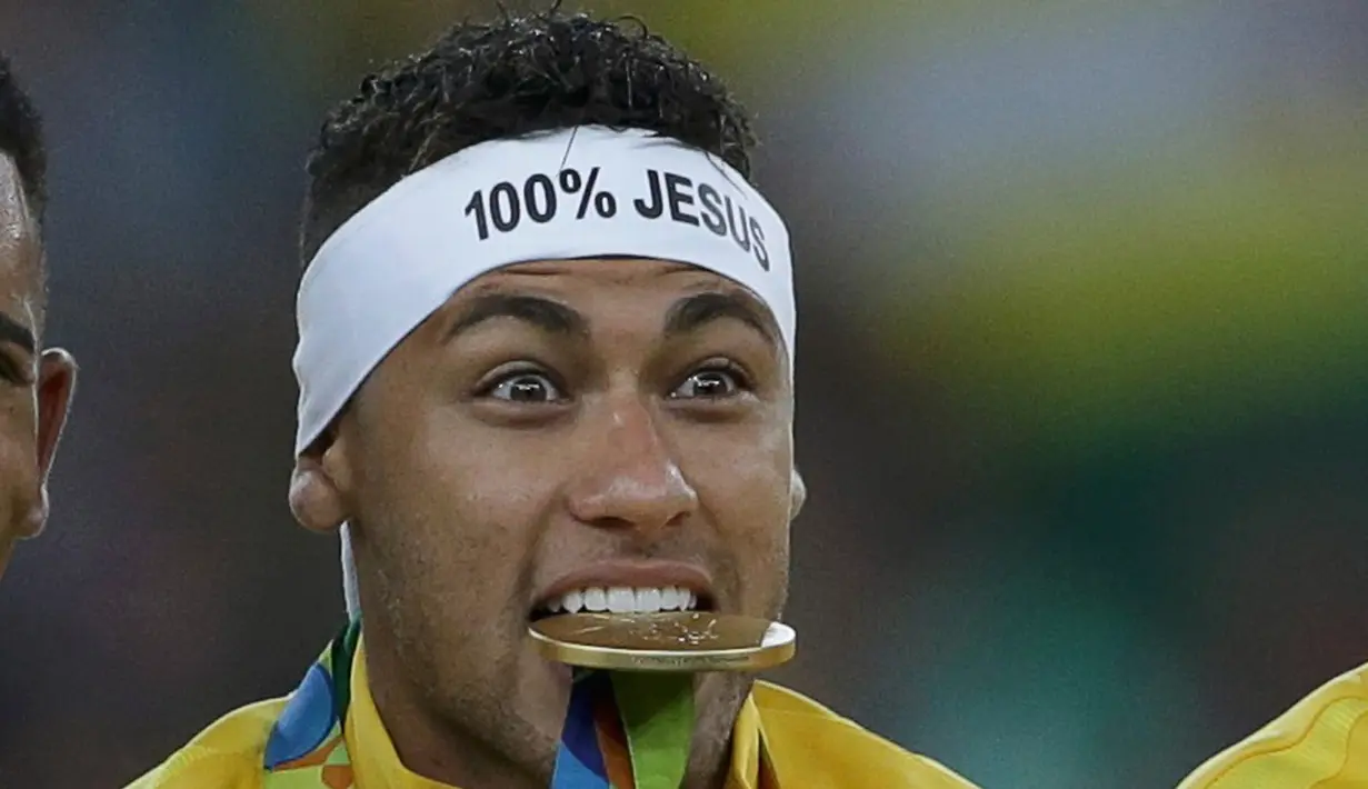 Pemain Timnas Brasil Neymar (10) mengigit medali emas setelah mengalahkan tim kesebelasan Jerman dalam adu penalti di partai final turnamen sepak bola Olimpiade Rio 2016 di Brasil (20/08) (REUTERS / Bruno Kelly)