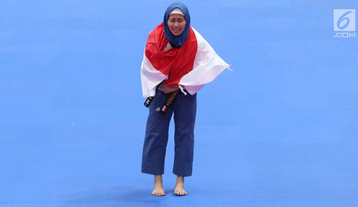 Atlet Taekwondo putri Indonesia, Defia Rosmaniar berselimut bendera Merah Putih saat merayakan kemenangan atas Salahshouri Marjan (Iran) pada Final Women Individual Poomsae di JCC, Jakarta, Minggu (19/8). (Liputan6.com/Helmi Fithriansyah)