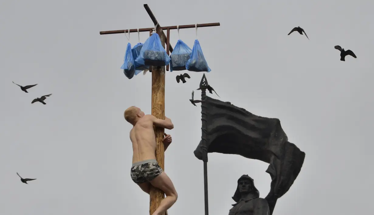Seorang pria memanjat tiang kayu selama perayaan Maslenitsa di kota Krasnoyarsk, Rusia, (13/3). perayaan Maslenitsa adalah kegiatan untuk menandai berakhirnya musim dingin di Rusia. (REUTERS/Yuri Maltsev)