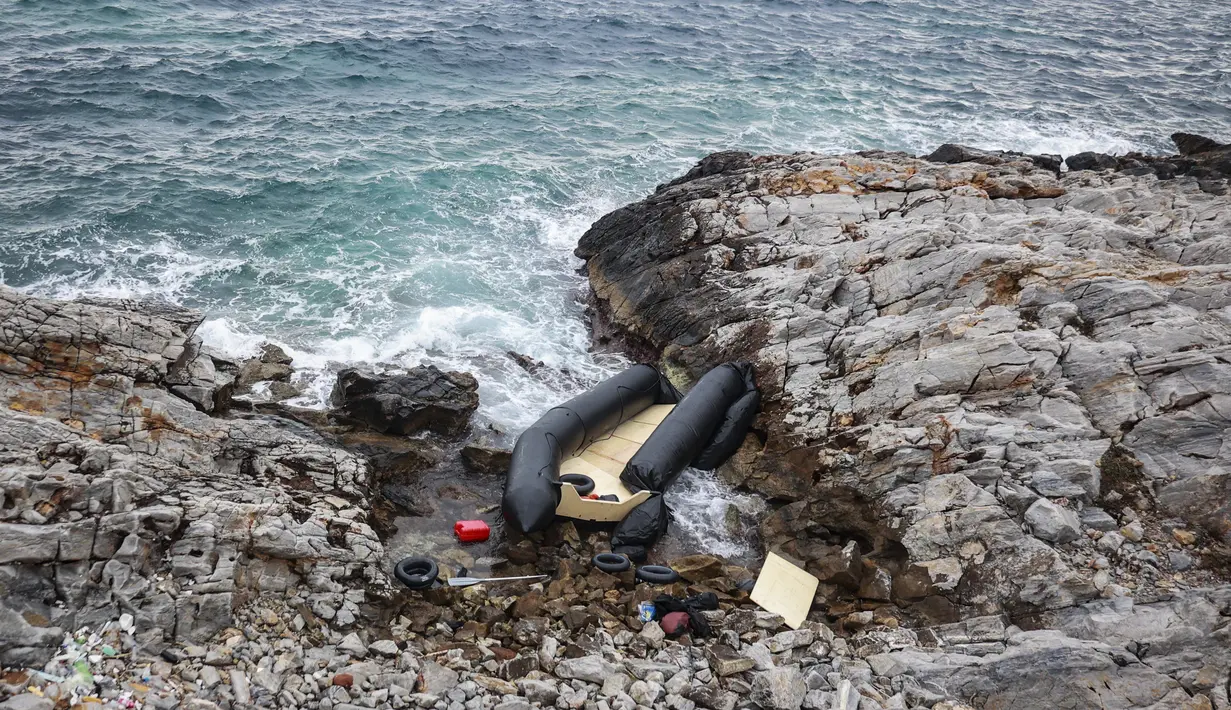 Sebuah perahu karet, yang diyakini digunakan oleh para migran, hancur di garis pantai berbatu, di Thermi di pulau Lesbos Yunani pada 7 Februari 2023. Sebuah kapal yang membawa migran dari negara tetangga Turki tenggelam di lepas pantai. (Manolis Lagoutaris / AFP)