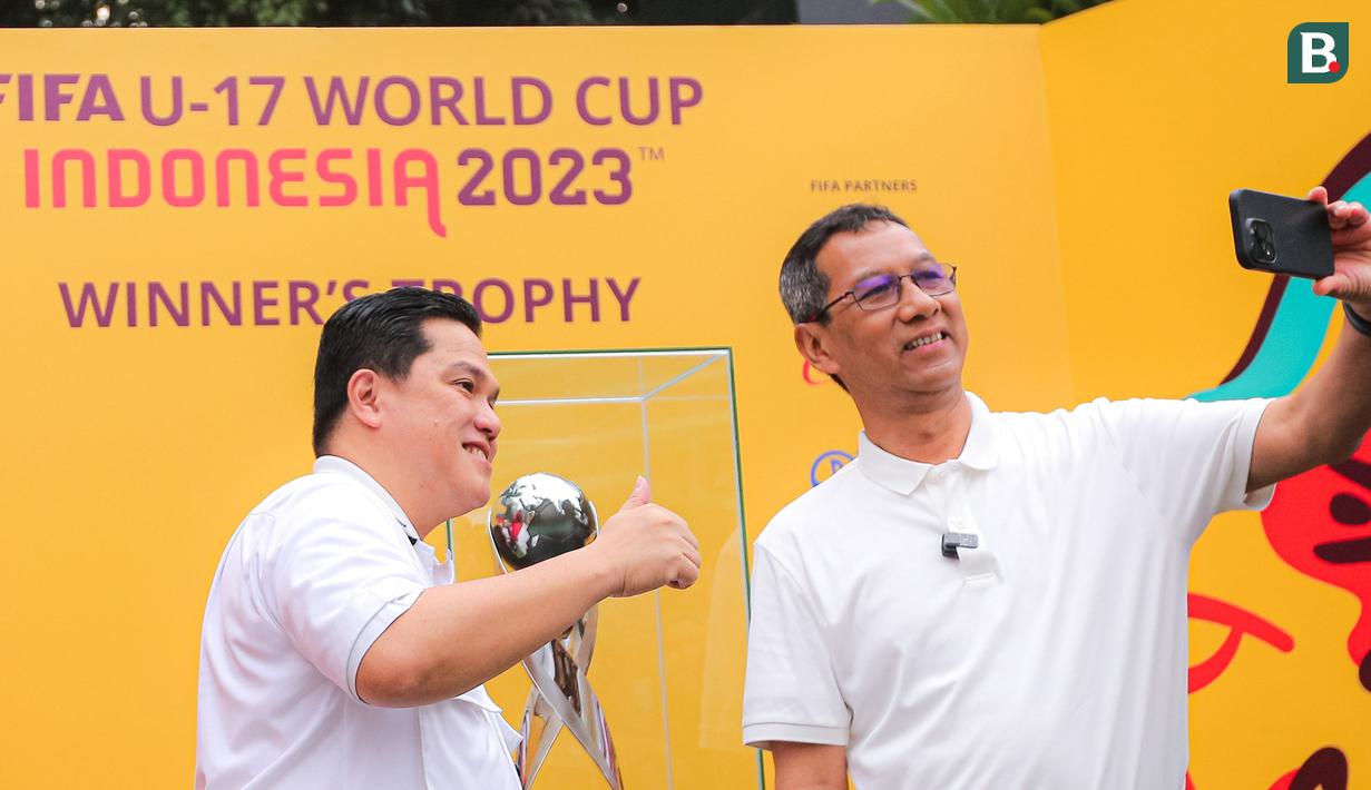 <p>Penjabat (Pj) Gubernur DKI Jakarta, Heru Budi Hartono (kanan), melakukan swafoto bersama Ketua PSSI, Erick Thohir, saat memamerkan trofi Piala Dunia U-17 2023 kepada masyarakat di Bundaran Hotel Indonesia (HI), Jakarta, Minggu (15/10/2023). (Bola.com/Bagaskara Lazuardi)</p>