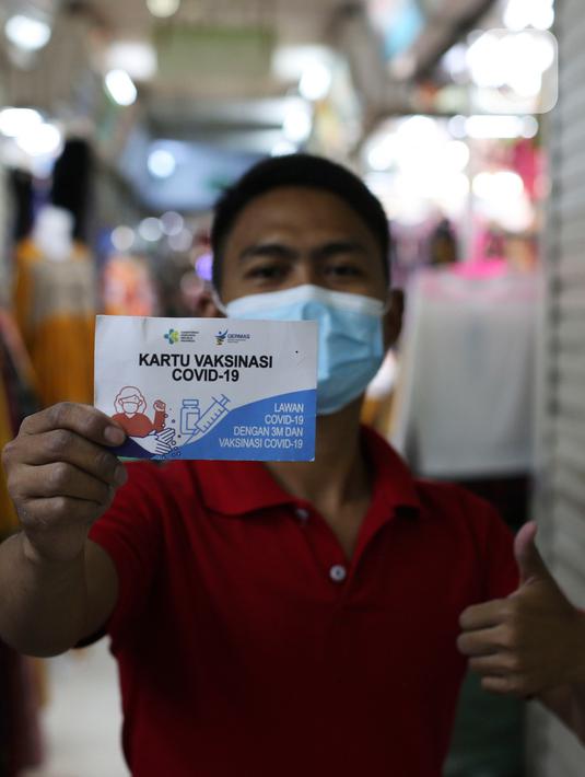 Pedagang melihatkan kartu vaksin di Pasar Tanah Abang, Jakarta, Selasa (27/7/2021). Dengan kembalinya dibuka Pasar Tanah Abang penjual mengeluhkan pembeli yang sangat sepi akibat peraturan baru yang mewajibkan menunjukkan kartu vaksin Covid-19 saat hendak berbelanja. (Liputan6.com/Johan Tallo)