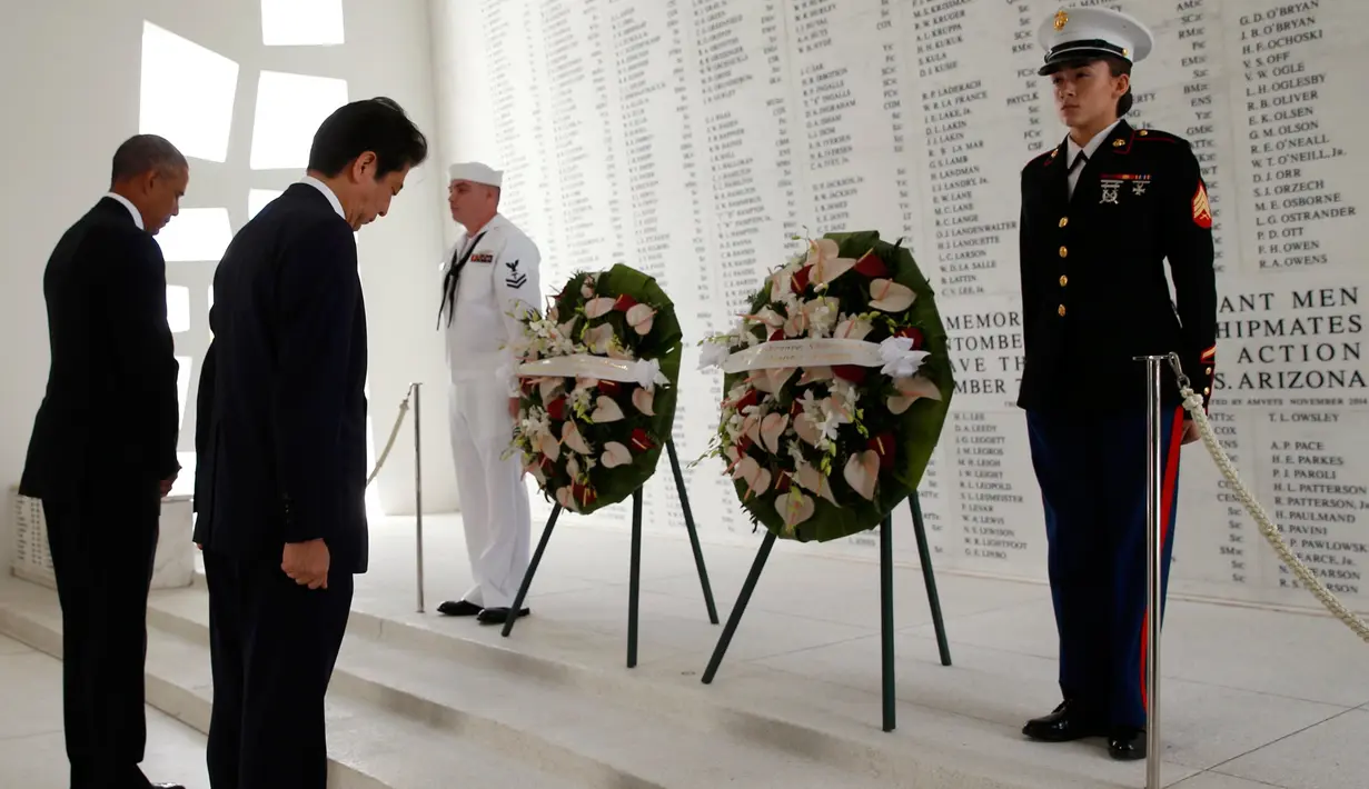 Presiden AS, Barack Obama dan PM Jepang, Shinzo Abe menundukan kepala saat upacara peletakan karangan bunga di atas kapal USS Arizona Memorial Perang Dunia II di Joint Base Pearl Harbor-Hickam, Hawaii, (27/12). (REUTERS/Kevin Lamarque)