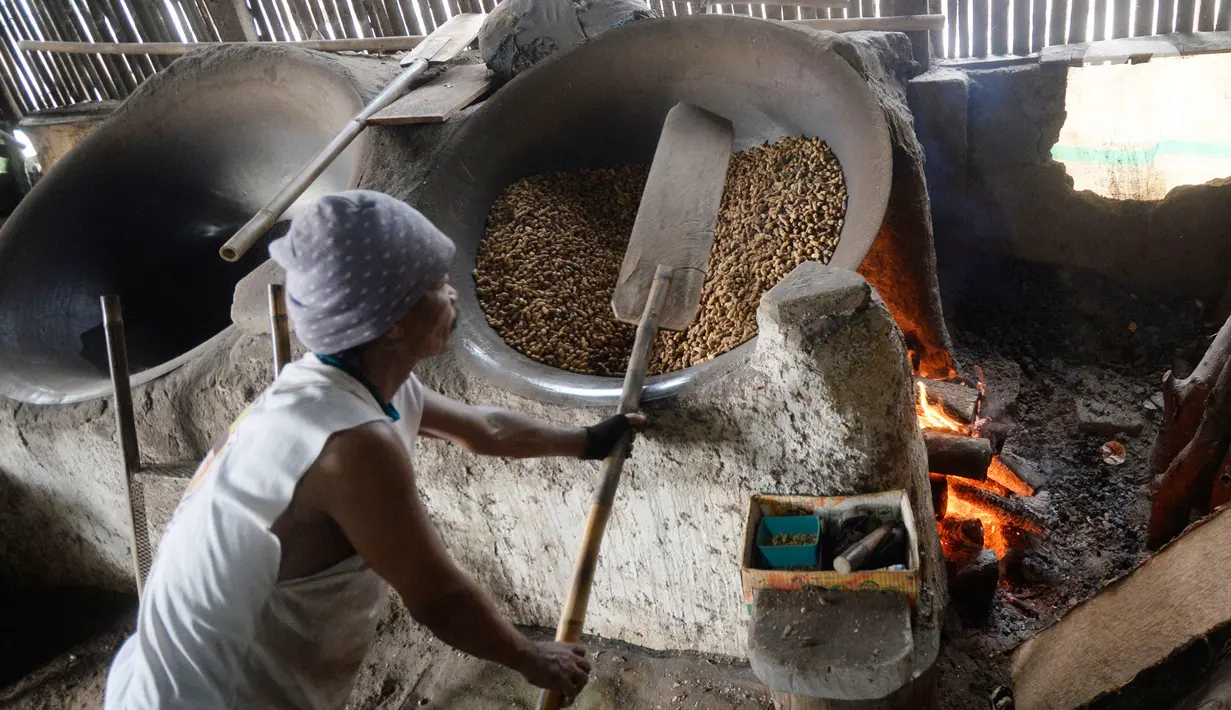 Pekerja mengolah kacang dengan media pasir di salah satu industri rumahan pembuatan kacang sangrai di Kawasan Keranggan, Tangerang Selatan, Selasa (11/8/2020). Kacang sangrai yang dipasarkan seharga Rp10.000 per kg itu mulai mengalami kenaikan pesanan dibanding bulan lalu. (merdeka.com/Dwi Narwoko)