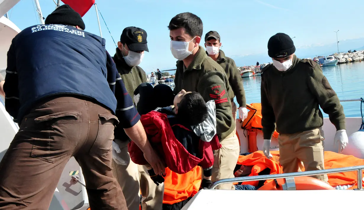 Petugas penyelamat saat menggotong mayat imigran di distrik Altinoluk, Balikesir, Turki, (8/2). Mayat imigran ini ditemukan sedang tenggelam saat mencoba menyeberang dari Turki ke Yunani. (STR / AFP)