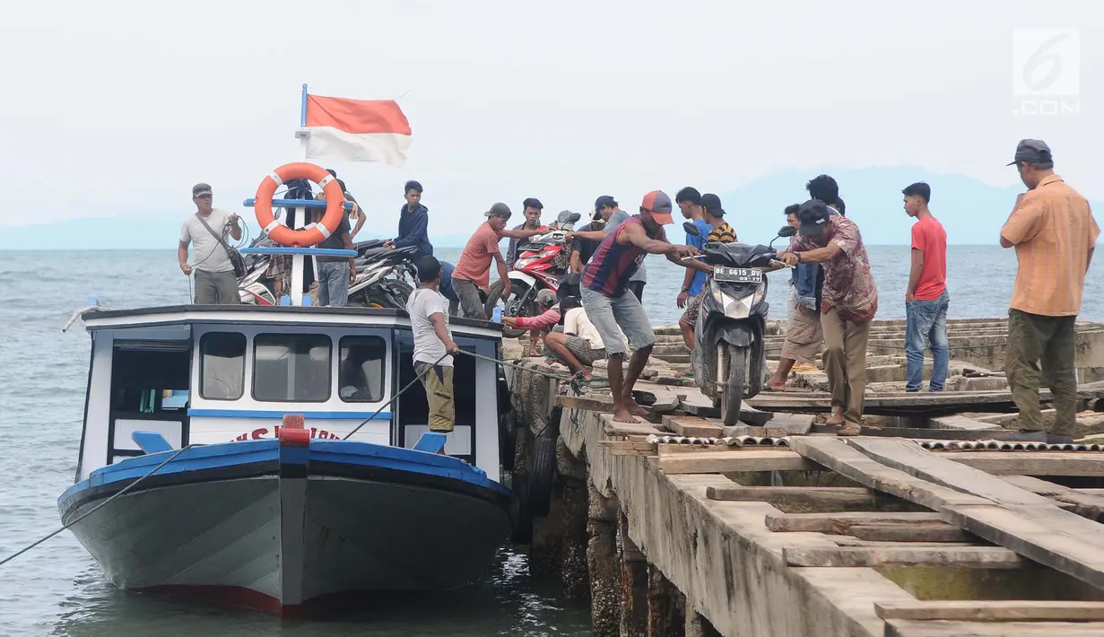 Petugas menurunkan motor dari kapal setibanya di dermaga Canti, Lampung, Senin (31/12). Setiap harinya hanya ada satu kapal yang menyeberang pada pukul 13.00 WIB dari Dermaga Canti ke Pulau Sebesi bertarif Rp 20.000/orang. (Liputan6.com/Herman Zakharia)