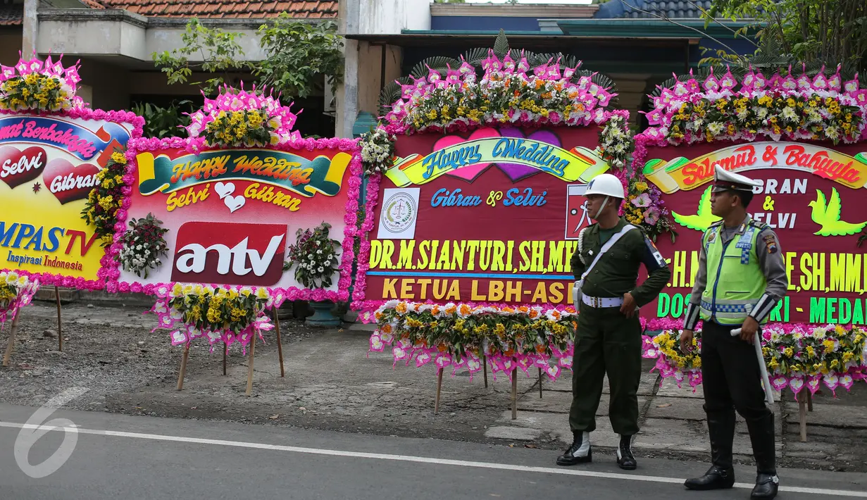 Sejumlah petugas berdiri di depan karangan bunga ucapan selamat, di sekitar tempat resepsi Gibran Rakabuming Raka-Selvi Ananda, di Gedung Graha Saba Buana, Solo, Rabu (10/6/2015). (Liputan6.com/Faizal Fanani)