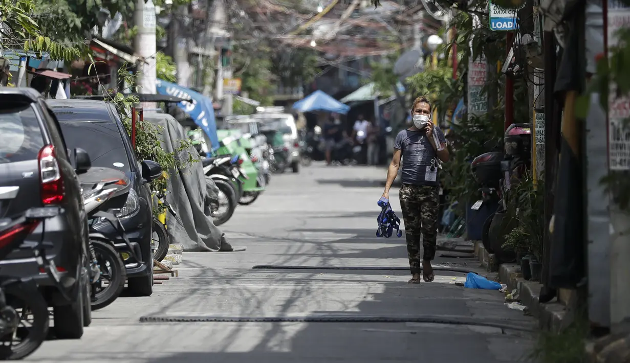 Seorang pria berjalan di sepanjang jalan kosong di sebuah desa yang dikunci karena jumlah kasus COVID-19 di antara penduduk di Manila, Filipina (11/3/2021).Departemen Kesehatan telah melaporkan lebih dari 603.000 kasus COVID-19, dengan 12.545 kematian. (AP Photo/Aaron Favila)