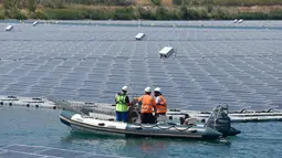 Petugas menggunakan perahu karet memeriksa panel surya fotovoltaik mengapung di kompleks pembangkit listrik O'Mega1 di Piolenc, Prancis selatan (30/7/2019). Pembangkit listrik tenaga surya (PLTS) mengapung pertama di Eropa ini akan beroperasi pada September 2019. (AFP Photo/Gerard Julien)