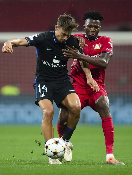 Bek Bayer Leverkusen Edmond Tapsoba berebut bola dengan gelandang Atletico Madrid Marcos Llorente dalam matchday kedua Grup B Liga Champions di BayArena, Rabu (14/9/2022) dini hari WIB. Bertandang ke markas Bayer Leverkusen, Atletico Madrid tumbang dengan skor 0-2. (Marius Becker/dpa via AP)