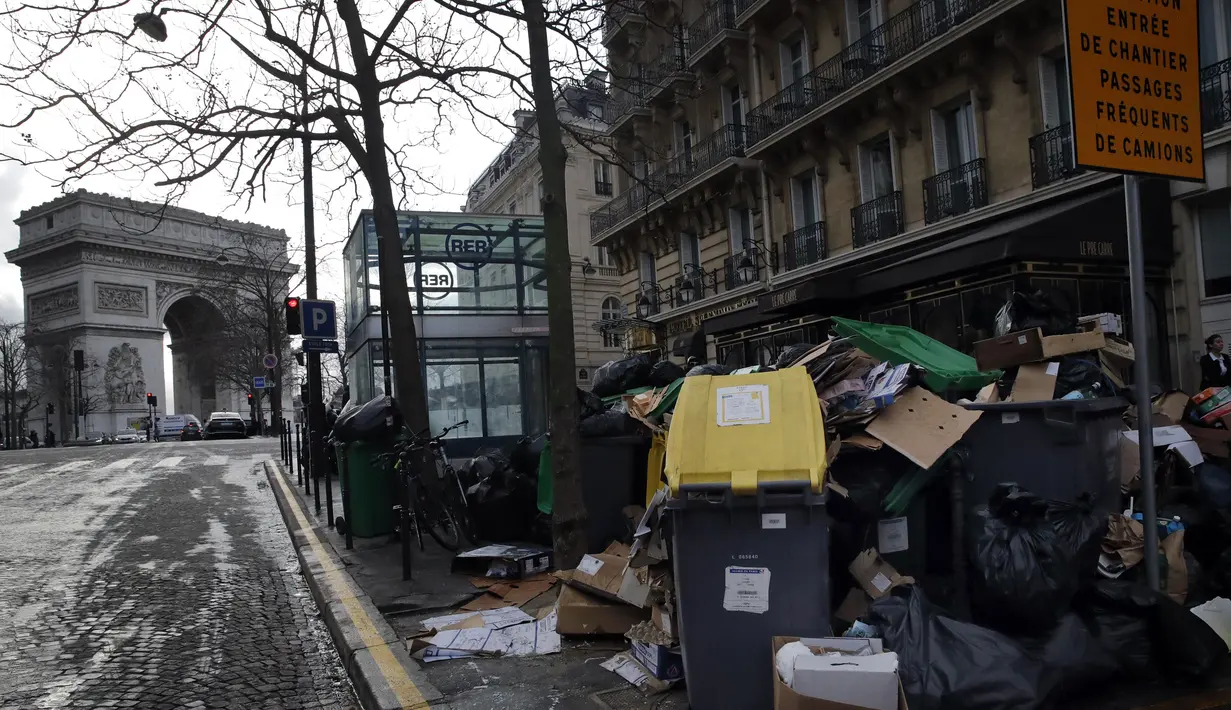 Orang-orang berjalan melewati tong sampah dan tumpukan kantong sampah yang menumpuk di Paris (4/2/2020). Sampah menumpuk di jalan-jalan Paris dan Marseille karena pemogokan perubahan pada sistem pensiun nasional Prancis.  (AP Photo/Christophe Ena)