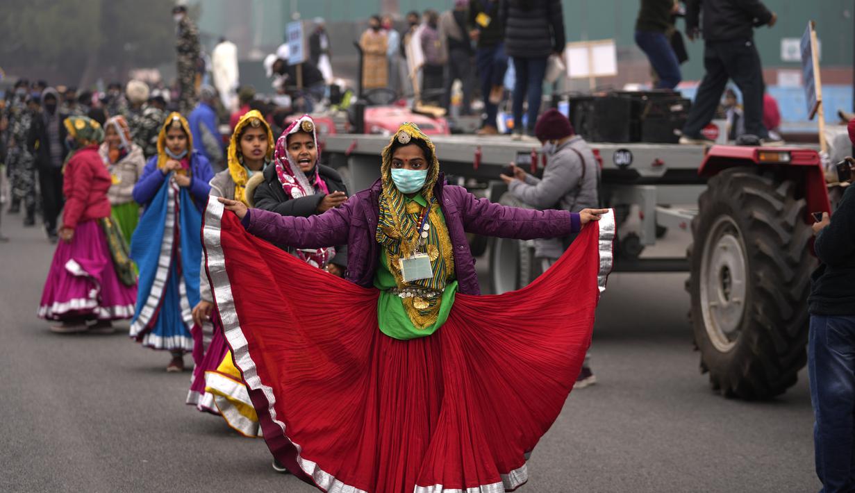 Seorang seniman yang mengenakan masker sebagai tindakan pencegahan terhadap virus corona menari dengan orang lain saat mereka berlatih untuk parade Hari Republik mendatang, di New Delhi, India (17/1/2022). India akan merayakan Hari Republik pada 26 Januari. (AP Photo/Manish Swarup)