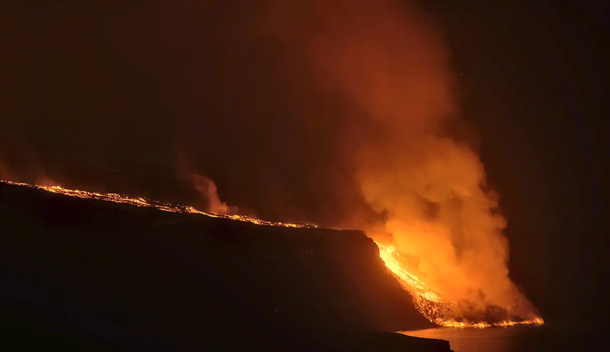 Pemandangan lava dari gunung berapi mencapai laut di pulau Canary La Palma, Spanyol, Rabu (29/9/2021) dinihari. Lava merah panas dari gunung berapi Cumbre Vieja mencapai Samudra Atlantik, sembilan hari setelah mulai mengalir menuruni gunung. (AP Photo/Daniel Roca)