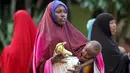 Seorang ibu sambil menggendong anaknya membawa iftar (makanan berbuka puasa) dari sebuah organisasi amal Qatar selama bulan suci Ramadan, di ibukota Mogadishu, Senin (22/6/2015). (REUTERS/Feisal Omar)