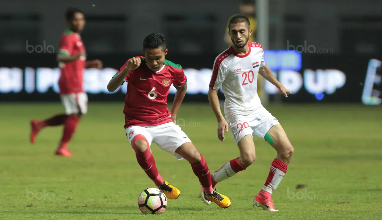 Pemain Timnas Indonesia U-23, Evan Dimas (kiri) mengecoh pemain Suriah U-23, Ahmad Al Ahmad pada laga persahabatan di Stadion Wibawa Mukti, Bekasi, Rabu (16/11/2017). Indonesia kalah 2-3. (Bola.com/NIcklas Hanoatubun)