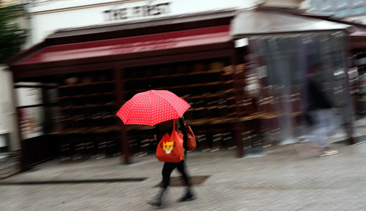 Seorang perempuan berjalan melewati tumpukan kursi dan meja dari bar The First yang tutup di Brussel, Belgia, Kamis (8/10/2020). Brussels pada Rabu (7/10), memutuskan menutup semua bar, ruang dansa, dan kafetaria selama sebulan sebagai upaya membendung lonjakan COVID-19. (AP Photo/Francisco Seco)