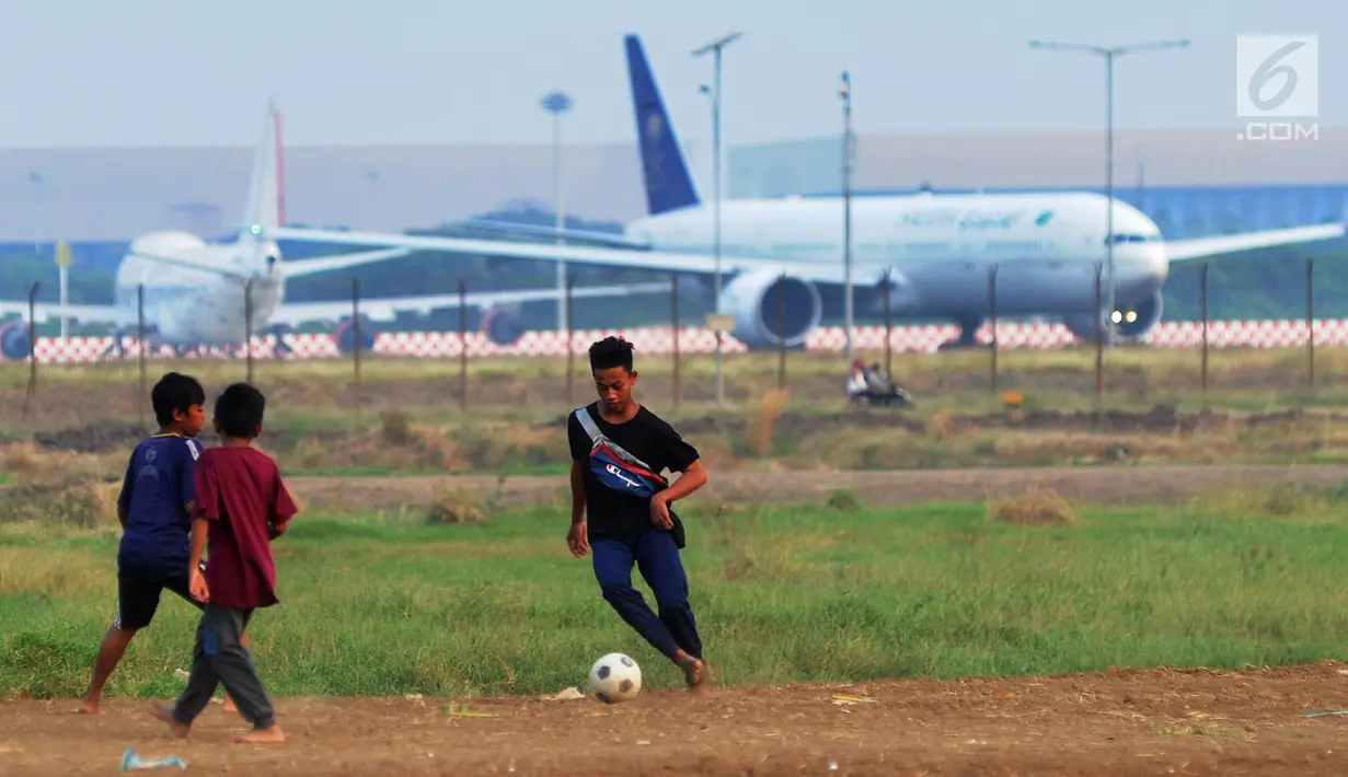 Anak-anak bermain bola di kawasan proyek perluasan landasan pacu atau Runway 3A Bandara Soekarno-Hatta (Soetta), Rawa Bokor, Tangerang, Banten, Selasa (2/7/2019). Mereka memanfaatkan lahan kosong yang belum dikerjakan pihak kontraktor untuk bermain bola. (merdeka.com/Arie Basuki)