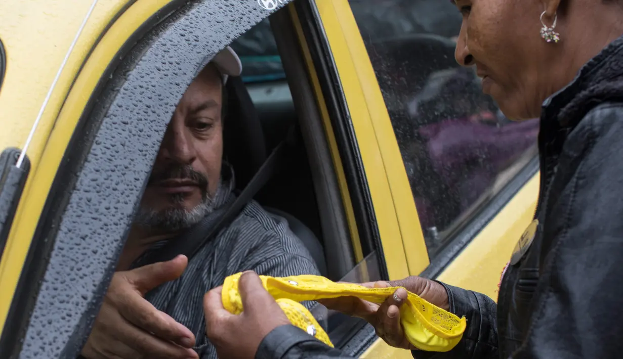 Seorang sopir taksi membeli celana dalam kuning di Medellin, Kolombia, Jumat (29/12). Menyambut perayaan tahun baru, celana dalam berwarna kuning banyak diburu warga Kolombia. (Joaquin SARMIENTO / AFP)
