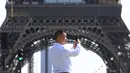 Seorang turis mengambil gambar dekat Menara Eiffel di Paris, Rabu (31/8/2022). Pariwisata kembali dengan sepenuh hati ke Prancis musim panas ini, mengirimkan pendapatan melebihi tingkat pra-pandemi menurut data pemerintah yang dirilis minggu ini. (AP Photo/Aurelien Morissard)