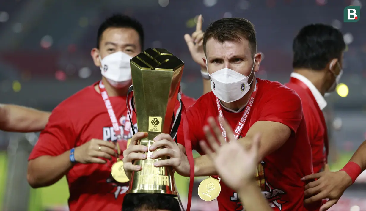 Pemain Persija Jakarta, Marco Motta, melakukan selebrasi dengan mengangkat trofi usai menjuarai Piala Menpora 2021 di Stadion Manahan, Solo, Minggu (25/4/2021). (Bola.com/M Iqbal Ichsan)