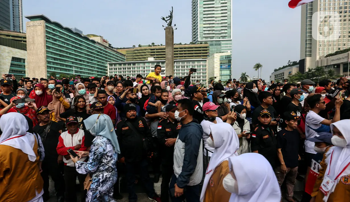 Warga yang sedang berolahraga saat pelaksanaan Car Free Day (CFD) menyaksikan iring-iringan Kirab Merah Putih di kawasan Bundaran HI, Jakarta, Minggu (28/8/2022). Sebanyak 50.000 orang membentangkan bendera merah putih sepanjang 1.700 meter dari kawasan Monas hingga Bundaran Hotel Indonesia dalam rangka memperingati HUT ke-77 Kemerdekaan Republik Indonesia bertemakan 'Pulih Lebih Cepat, Bangkit Lebih Kuat. (Liputan6.com/Johan Tallo)
