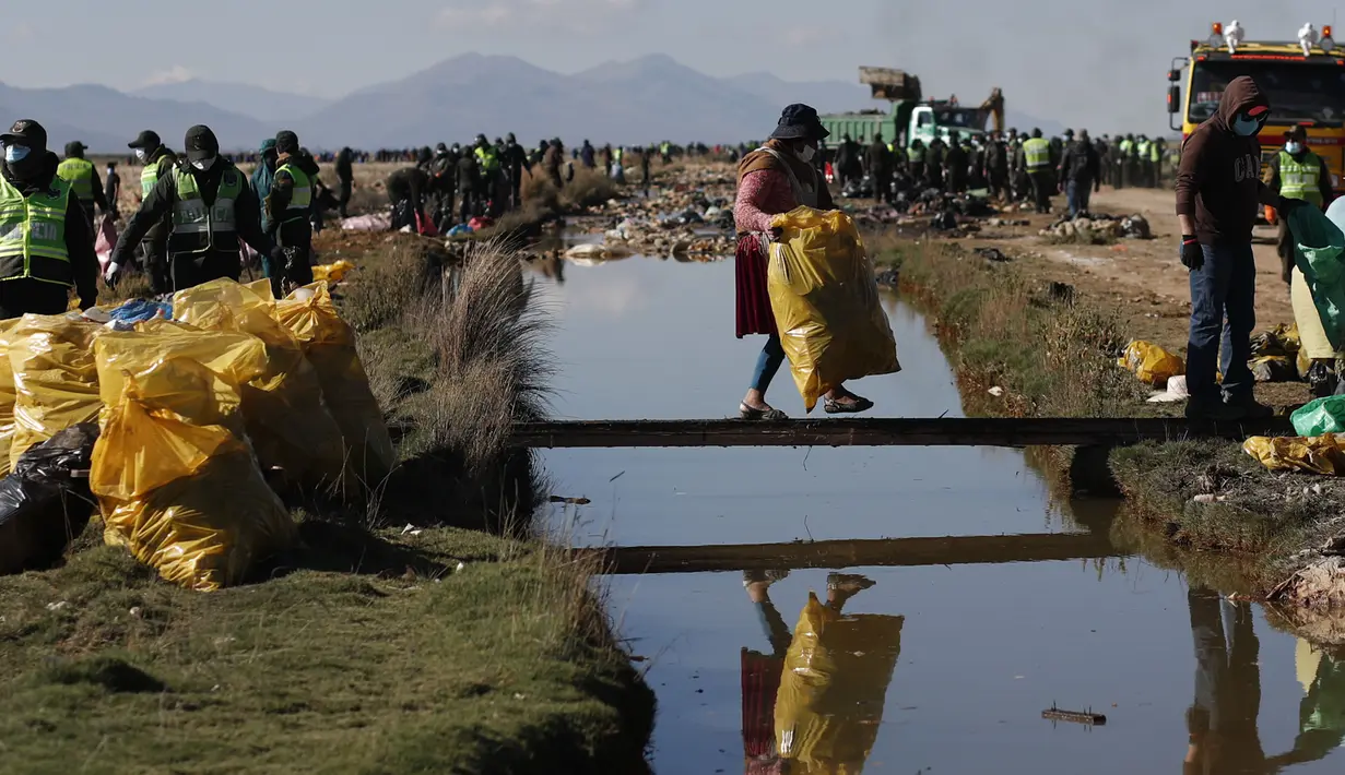 Relawan membawa kantong berisi sampah yang dikumpulkan dari Sungai Tagaret, yang mengalir ke Danau Uru Uru, dekat Oruro, Bolivia, Rabu (7/4/2021). Operasi pembersihan dimulai dalam upaya mengembalikan danau ke keindahan alamnya yang telah dibanjiri sampah plastik dan limbah lainnya. (AP/Juan Kari)