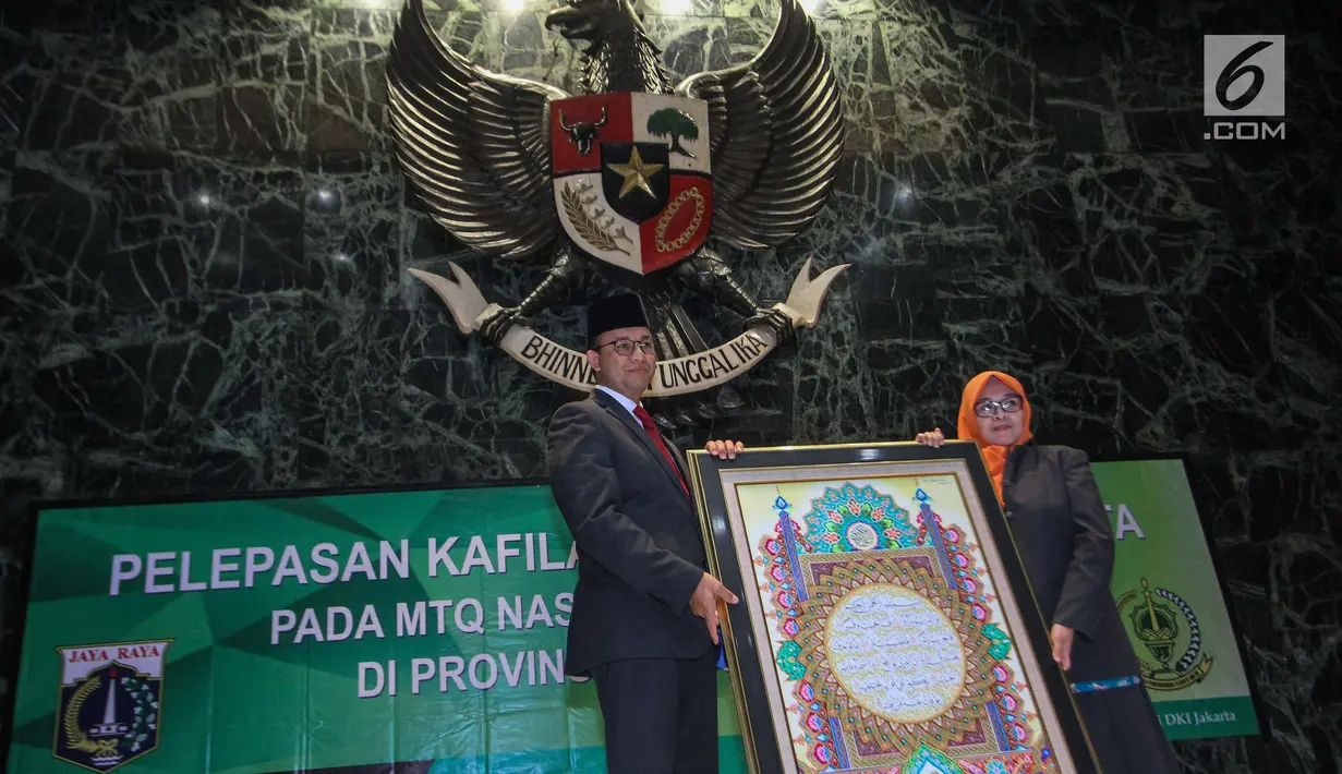 Gubernur DKI Jakarta Anies Baswedan memegang kaligrafi Alquran saat melapas Kafilah Provinsi DKI Jakarta untuk mengikuti MTQ Tingkat Nasional XXVII, Jakarta, Kamis (4/10). Anies berharap Kafilah DKI dapat meraih juara umum. (Liputan6.com/Faizal Fanani)