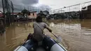 Seorang pria menaiki perahu karet saat menyusuri banjir yang melanda Jalan Bina Warga Rt 005/Rw 07 Kelurahan Rawa Jati, Jakarta, Senin (8/2/2021). Banjir setinggi 60-190 cm tersebut disebabkan oleh luapan air Sungai Ciliwung dan curah hujan Jakarta yang tinggi. (Liputan6.com/Johan Tallo)