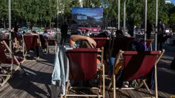 Orang-orang menghadiri Cinema on the Water, yang diselenggarakan Paris Plages selama pemutaran "Le Grand Bain" di Paris, Prancis pada 18 Juli 2020. Paris menghadirkan terobosan baru dengan bioskop terapung lengkap dengan perahu yang tetap menjaga jarak. (AP Photo/Rafael Yaghobzadeh)