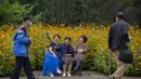 Wanita berpose selfie dengan bunga mekar di taman umum di Beijing, Sabtu (2/10/2021). Pengunjung memadati taman dan lokasi wisata di Beijing saat China merayakan hari kedua masa libur Hari Nasional. (AP Photo/Mark Schiefelbein)