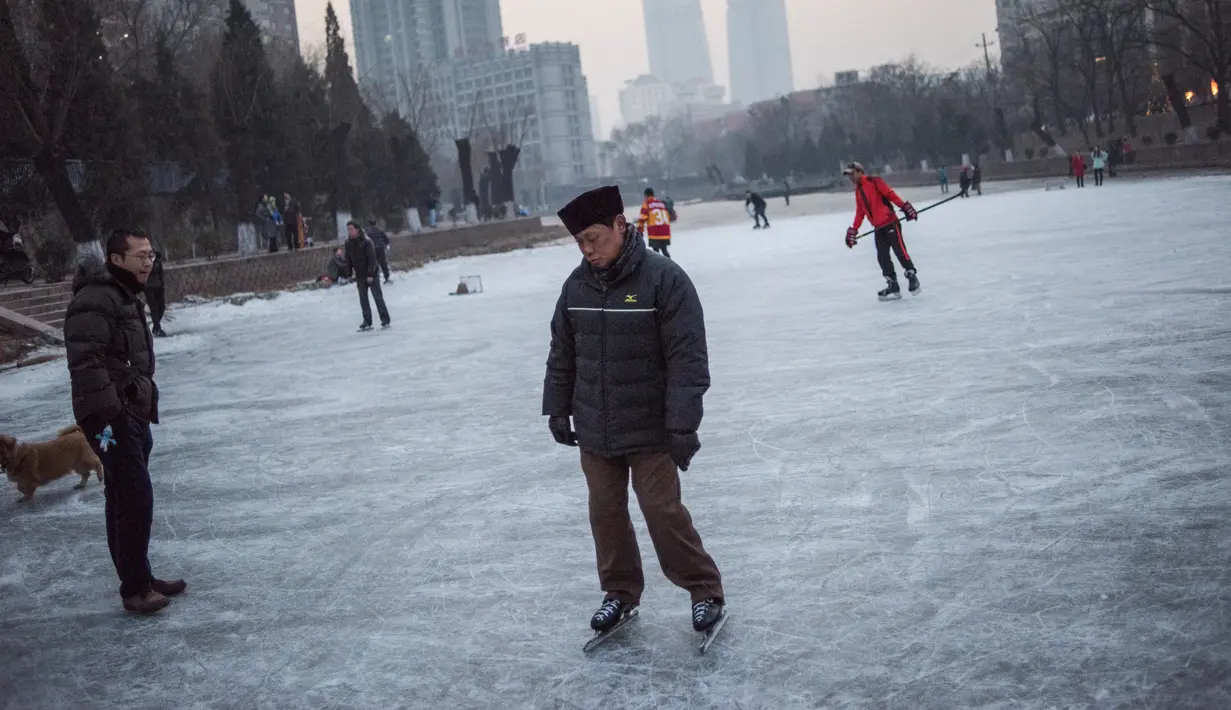 Aksi seorang pria saat bermain ice skating atau seluncur es di atas sungai yang telah membeku di Beijing, Jumat (1/1). Semenjak membeku, sungai di Beijing ini menjadi objek wisata dadakan yang banyak diminati wisatawan.  (AFP/Fred Dufour)