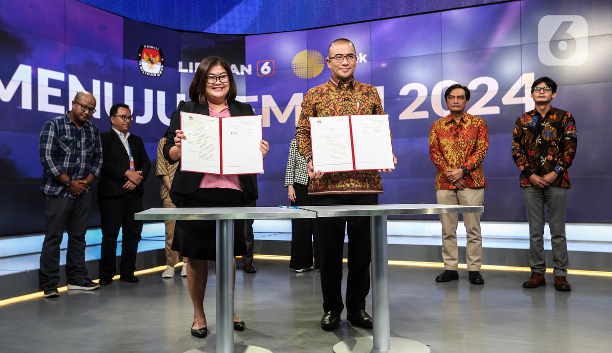 Ketua Komisi Pemilihan Umum (KPU) Hasyim Asy'ari (tengah kanan) bersama CFO KLY Octaviany Sarimawan (tengah kiri) menunjukkan dokumen kerja sama saat acara penandatanganan MoU antara Emtek dengan KPU di SCTV Tower, Jakarta, Selasa (30/8/2022). Kerja sama KPU dengan Emtek ini terkait sosialisasi Pemilihan Umum yang akan diselenggarakan 2024 mendatang. (Liputan6.com/Johan Tallo)
