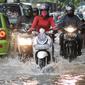Pengendara motor menerobos genangan air di Pejaten Raya, Jakarta, Selasa (4/10). Akibat curah hujan yang tinggi menyebabkan sejumlah titik di Jakarta tergenang air. (Liputan6.com/Yoppy Renato)