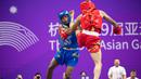 Atlet wushu Indonesia, Samuel Marbun (kiri) berusaha mengadang tendangan atlet wushu Iran, Afsin Shalimi pada laga final cabor wushu nomor sanda kelas 65kg putra Asian Games 2022 di Xiaoshan Guali Sports Centre, Hangzhou, China, Kamis (28/9/2023). (NOC Indonesia/Naif Al'as)