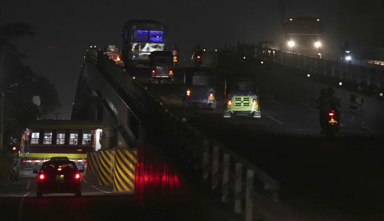 Kereta api dan kendaraan melaju dalam kegelapan selama pemadaman listrik di Kelaniya, Sri Lanka, 5 Maret 2022. Krisis keuangan negara memaksa anak-anak belajar menggunakan lampu minyak tanah, nelayan mengurangi penangkapan ikan dan industri membatasi produksi. (AP Photo/Eranga Jayawardena)