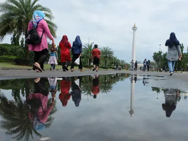 Sejumlah pengunjung berjalan saat sedang liburan di Monumen Nasional (monas), Jakarta, Selasa (25/12). Liburan Natal 2018, banyak warga datang bersama kerabat maupun keluarga memadati Monas. (Liputan6.com/Herman Zakharia)