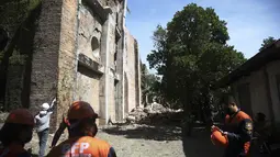 Petugas pemadam kebakaran berdiri di samping gereja yang rusak setelah gempa kuat di Ilocos Norte, Filipina Utara, Rabu (26/10/2022). Gempa kuat mengguncang sebagian besar Filipina utara, melukai banyak orang dan memaksa penutupan bandara internasional dan bandara. evakuasi pasien di rumah sakit. (AP Photo)