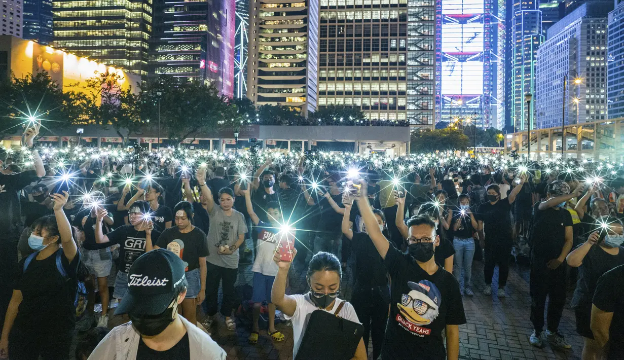 Mahasiswa menyalakan ponselnya sambil menyanyikan 'Do You Hear the People Sing' dari 'Les Miserables' selama rapat umum di Hong Kong (22/8/2019). Boikot ini disebabkan karena masa perkuliahan mendatang waktunya bertabrakan dengan unjuk rasa massa pro-demokrasi. (AFP Photo/Anthony Wallace)