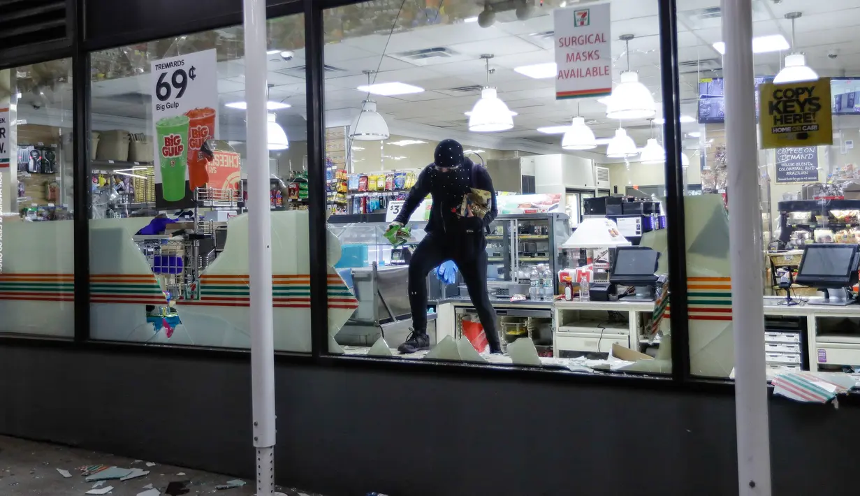 Seseorang membawa barang yang dijarah dari toko 7-Eleven di New York, AS (1/6/2020). Sejumlah toko di Amerika Serikat dijarah oleh pendemo yhang mengecam kematian warga kulit hitam George Floyd. (AP Photo/Frank Franklin II)