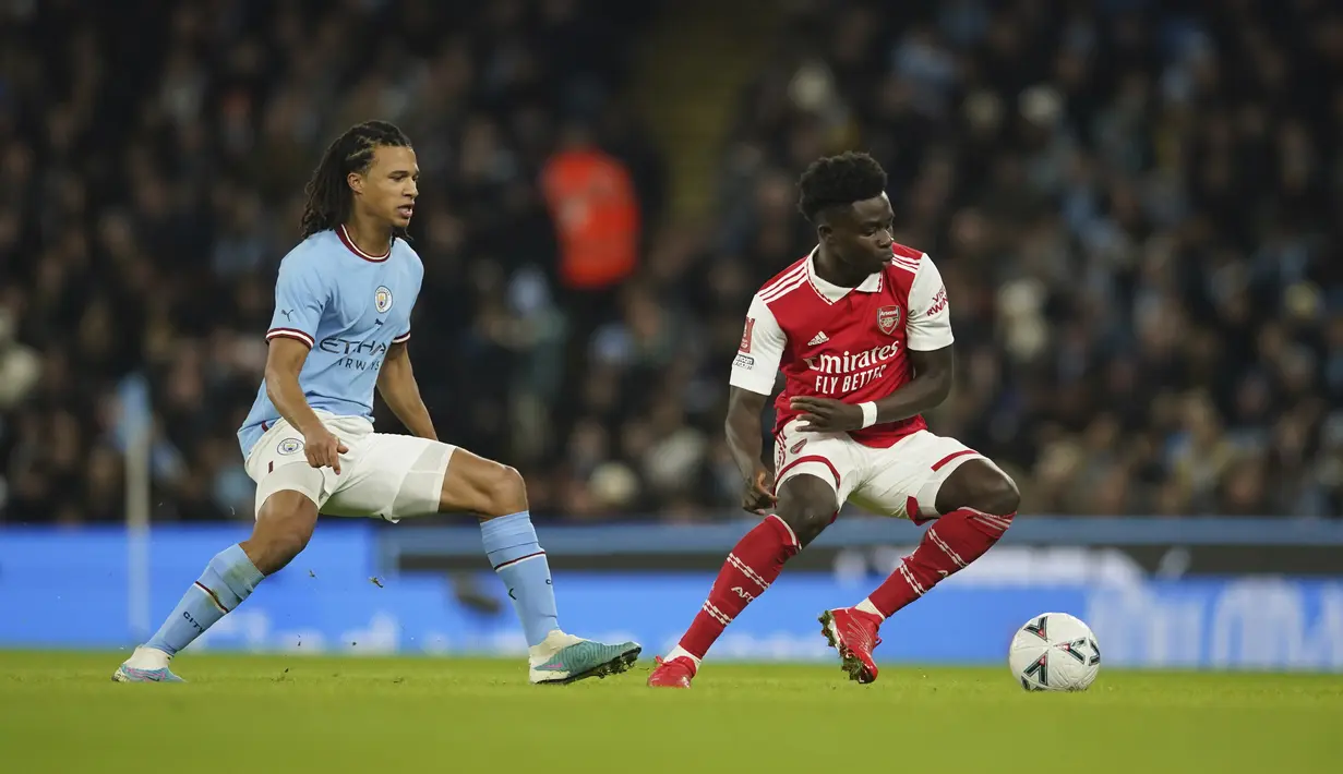 Gelandang Bukayo Saka dari Arsenal mencoba menggiring bola melewati Nathan Ake dari Manchester City selama pertandingan selama pertandingan putaran keempat Piala FA di Stadion Etihad di Manchester, Inggris, Sabtu (28/1/2023). Man City menang tipis atas Arsenal dengan skor 1-0. (AP Photo/Dave Thompson)