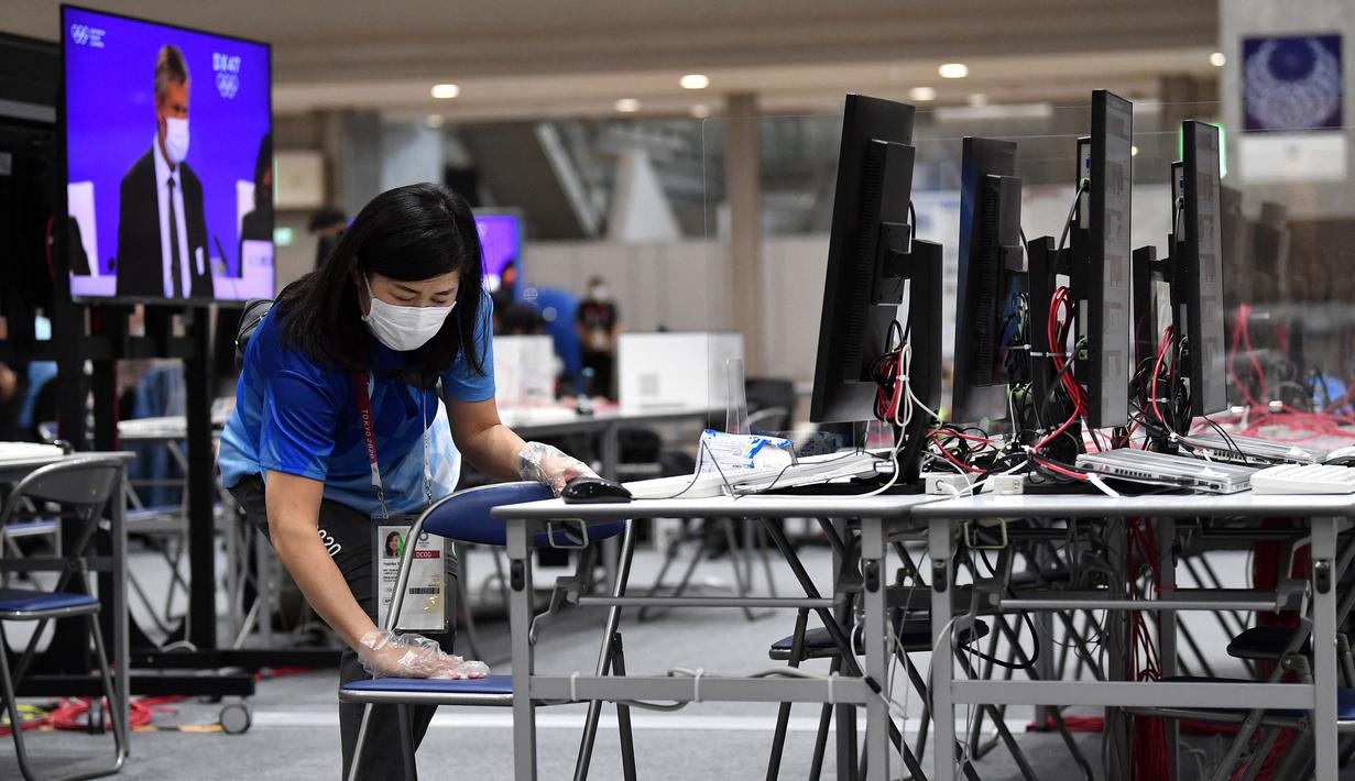 Seorang relawan membersihkan meja dengan tisu alkohol di Main Press Centre di Tokyo pada 20 Juli 2021, menjelang Olimpiade Tokyo 2020. (AFP/Jung Yeon-je)