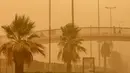 Warga berjalan di JPO saat terjangan badai pasir di Kuwait City, Kuwait, pada 17 Juni 2021. Terjangan badai pasir ini membuat jarak pandang atau visibilitas di beberapa daerah turun hingga kurang dari 100 meter. (AFP/YasserAl-Zayyat)