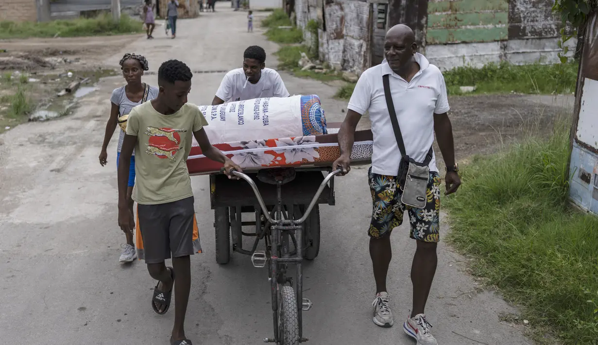 Warga lingkungan El Fanguito memindahkan barang-barang mereka ke tempat yang aman saat mereka mempersiapkan kedatangan Badai Ian, di Havana, Kuba, Senin, 26 September 2022. Badai Ian semakin kuat saat mendekati ujung barat Kuba pada trek untuk menghantam pantai barat Florida sebagai badai besar pada awal Rabu. (AP Photo/Ramon Espinosa)