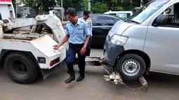 Petugas Dinas Perhubungan DKI Jakarta memasang alat derek untuk membawa mobil yang parkir di bahu jalan di kawasan Jatinegara, Jakarta, Senin (2/10). Razia parkir liar dilakukan untuk menertibkan kawasan tersebut. (Liputan6.com/Helmi Afandi)