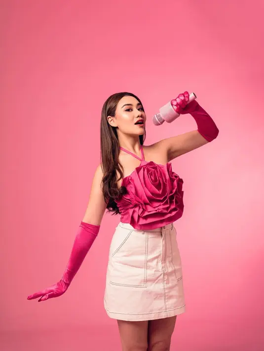 Di sini, Aaliyah Massaid menjelma jadi Barbie. Ia mengenakan atasan berbentuk bunga mawar besar dengan detail cross-neck, dipadu mini skirt putih dan gloves panjang berwarna pink yang serasi dengan atasannya. [Foto: Instagram/aaliyah.massaid]
